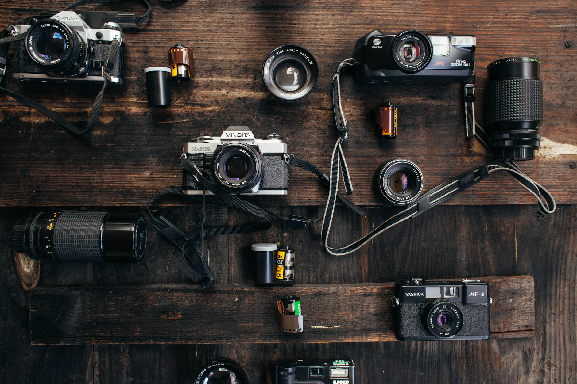 vintage cameras and lenses near camera roll on table