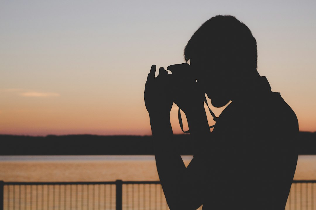 Silhouette of a photographer with camera at sunset, representing persistence through a creative plateau